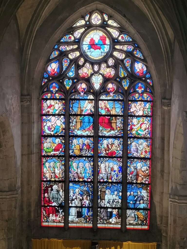Grand vitrail à médaillons narratifs de l'église de Saint-Gengoux-le-National, illustrant des scènes religieuses en couleurs vives