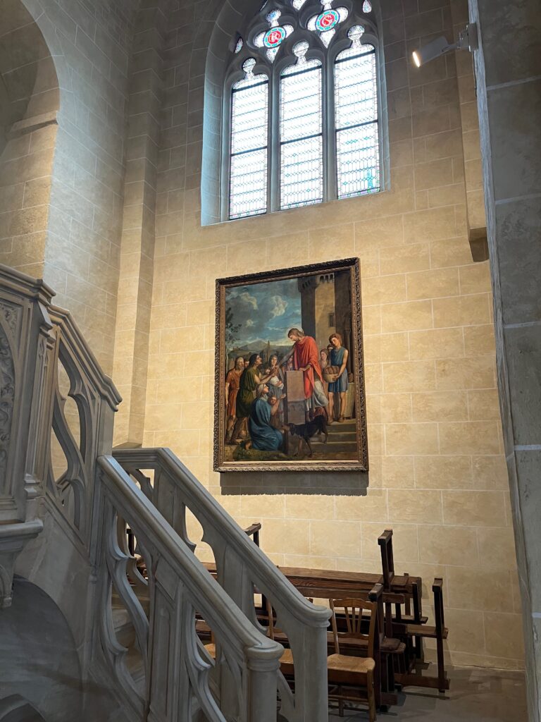 Tableau religieux représentant une scène de distribution d'aumônes aux pauvres, accroché dans l'escalier menant au chœur de l'église.